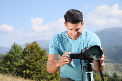 Photo of Professional photographer taking picture with modern camera in mountains