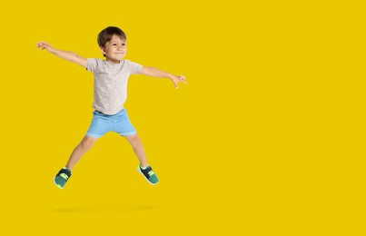 Image of Happy boy jumping on golden background, space for text
