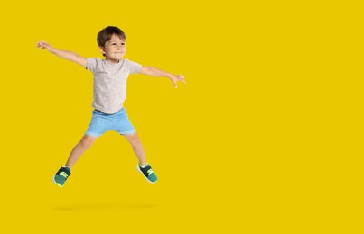 Happy boy jumping on golden background, space for text