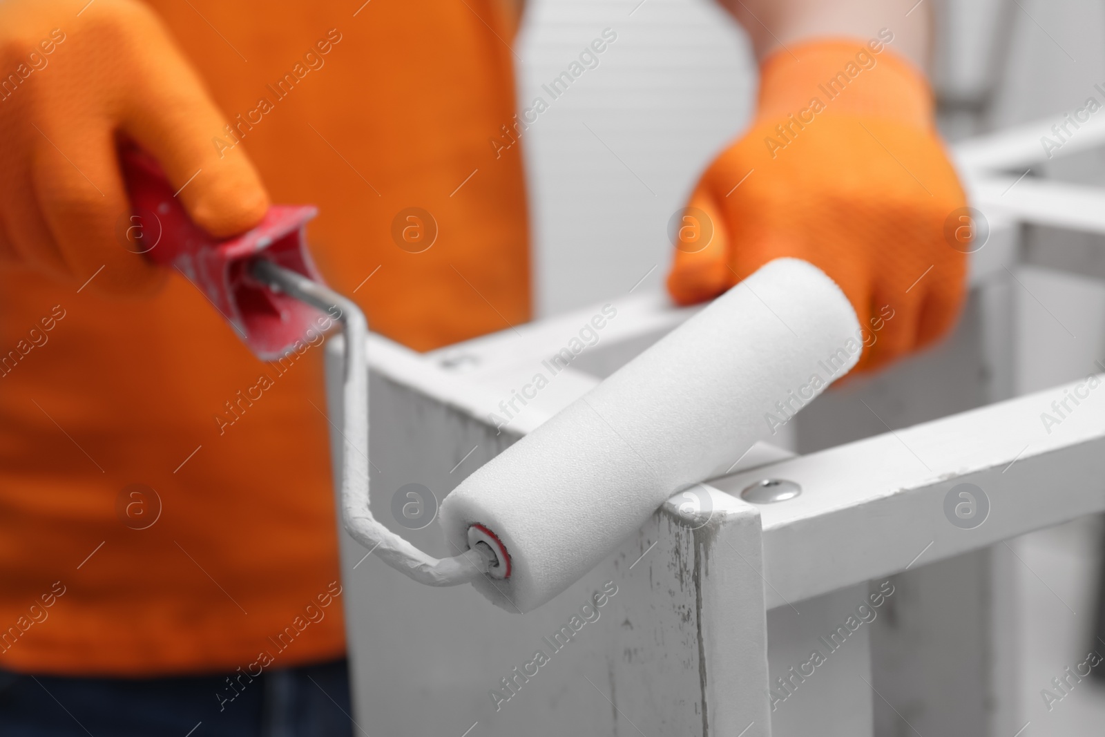 Photo of Man using roller to paint bekvam with white dye, closeup