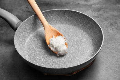 Photo of Frying pan with coconut oil on grey background, closeup