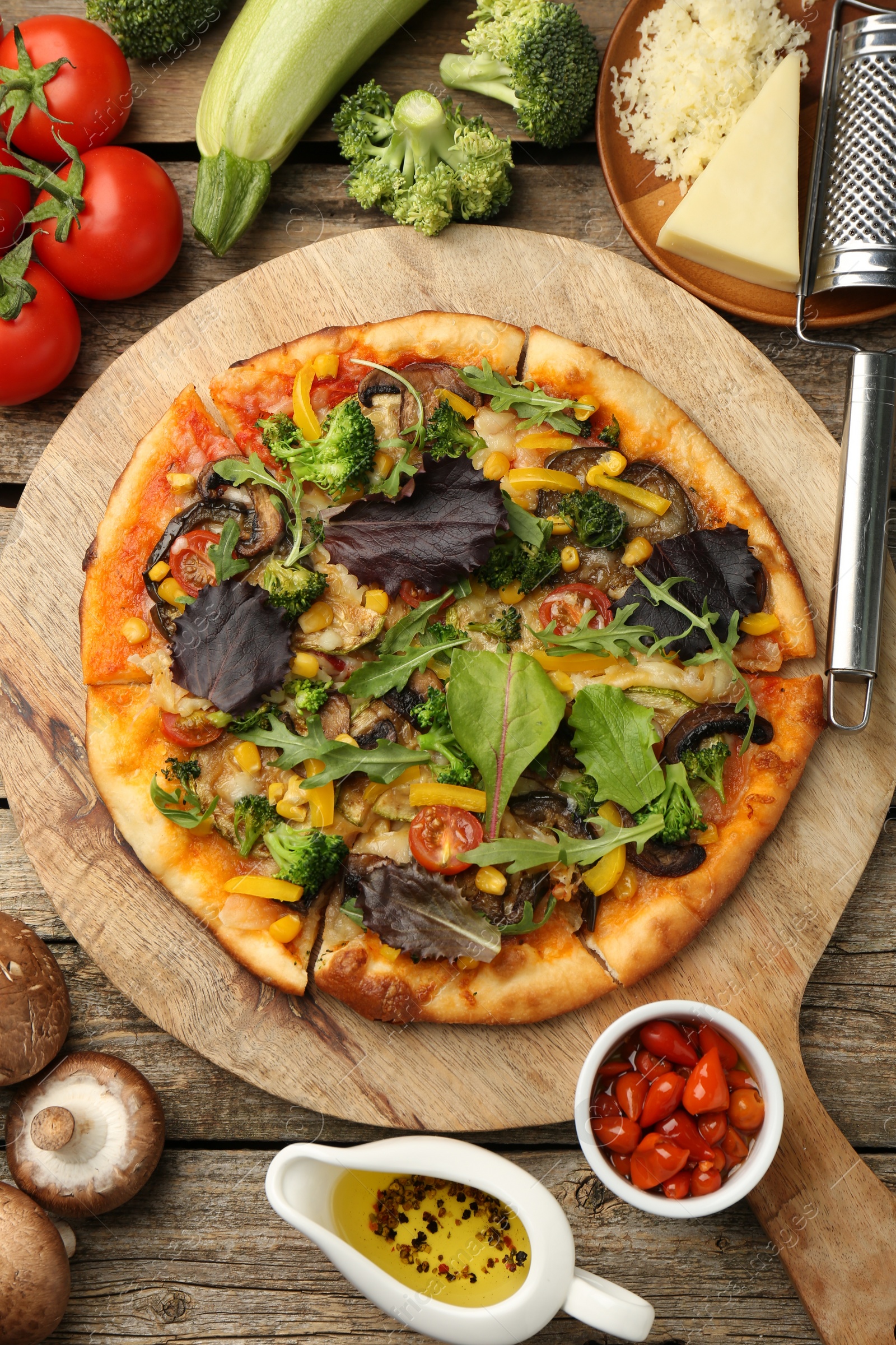 Photo of Delicious vegetarian pizza and ingredients on wooden table, flat lay