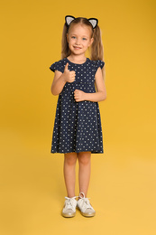 Photo of Portrait of cute little girl on yellow background