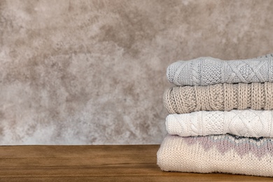 Photo of Stack of warm autumn clothes on wooden table. Space for text