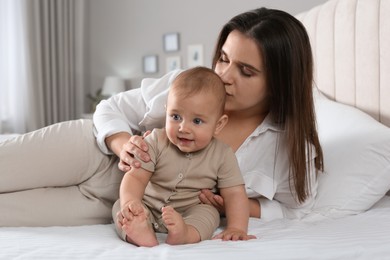 Photo of Happy young mother with her cute baby on bed at home