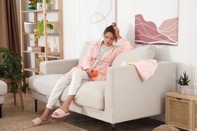 Photo of Tired young mother sitting on sofa in living room