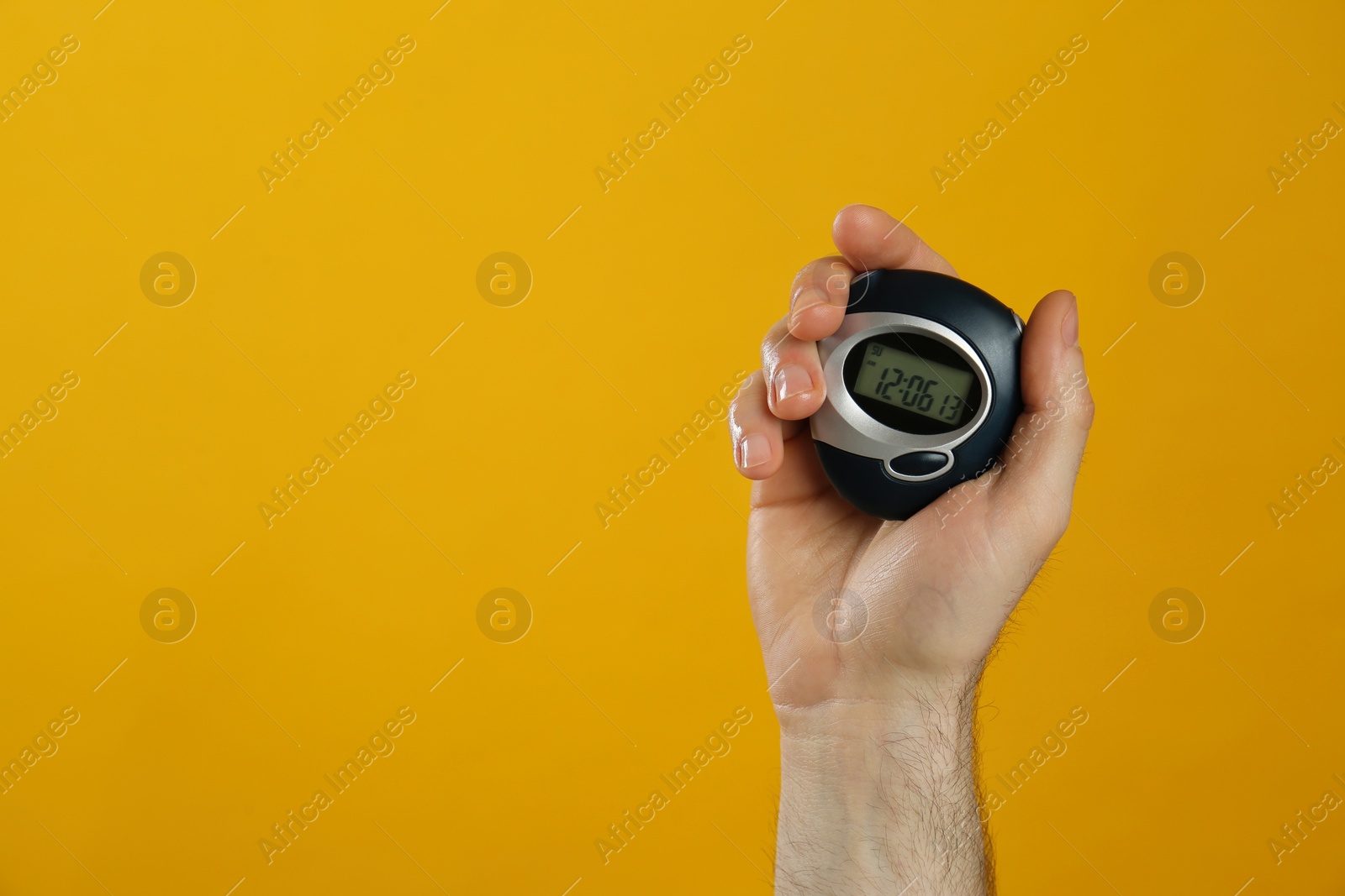 Photo of Man holding digital timer on yellow background, closeup. Space for text