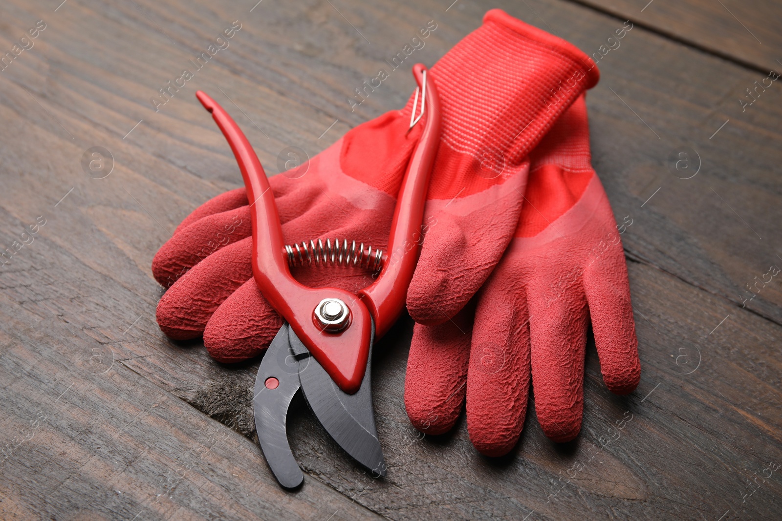 Photo of Pair of red gardening gloves and secateurs on wooden table