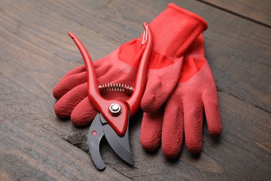 Pair of red gardening gloves and secateurs on wooden table