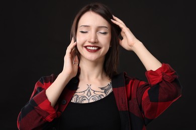 Photo of Portrait of smiling tattooed woman on black background