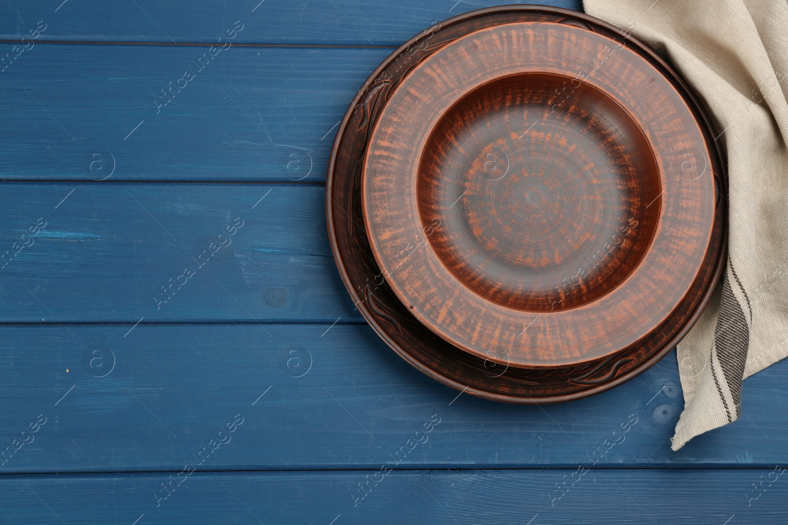 Photo of Clay plates on blue wooden table, flat lay. Space for text