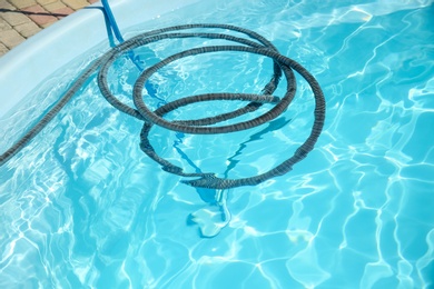 Photo of Cleaning outdoor swimming pool with underwater vacuum