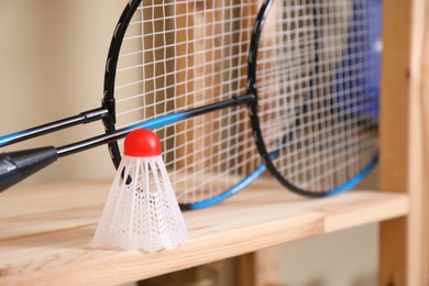 Photo of Badminton rackets and shuttlecock on wooden shelf, closeup