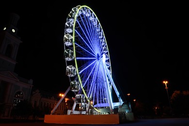 Beautiful glowing Ferris wheel on city street at night