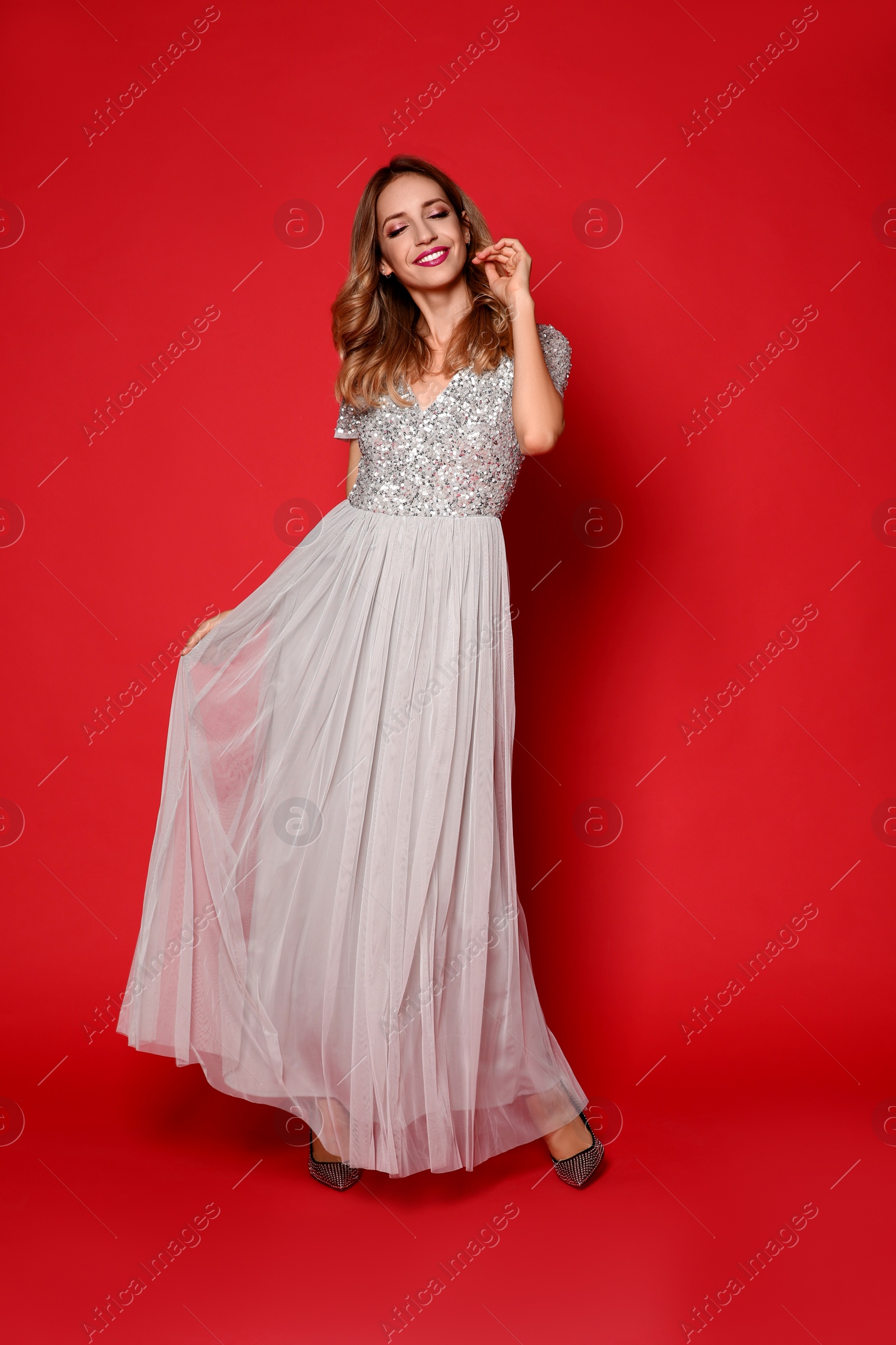 Photo of Happy woman in stylish dress on red background. Christmas party
