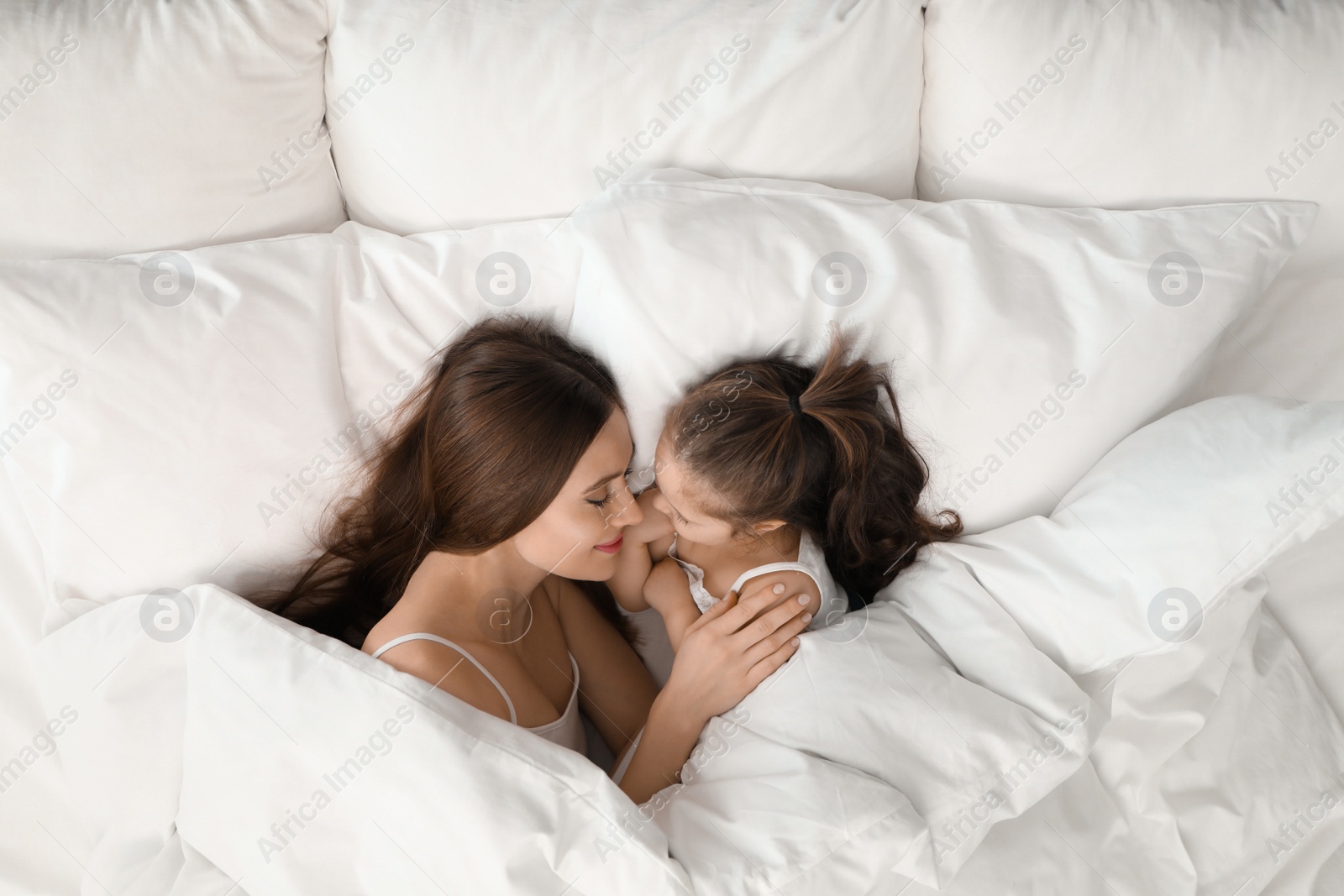 Photo of Mother and little daughter sleeping in bed, top view