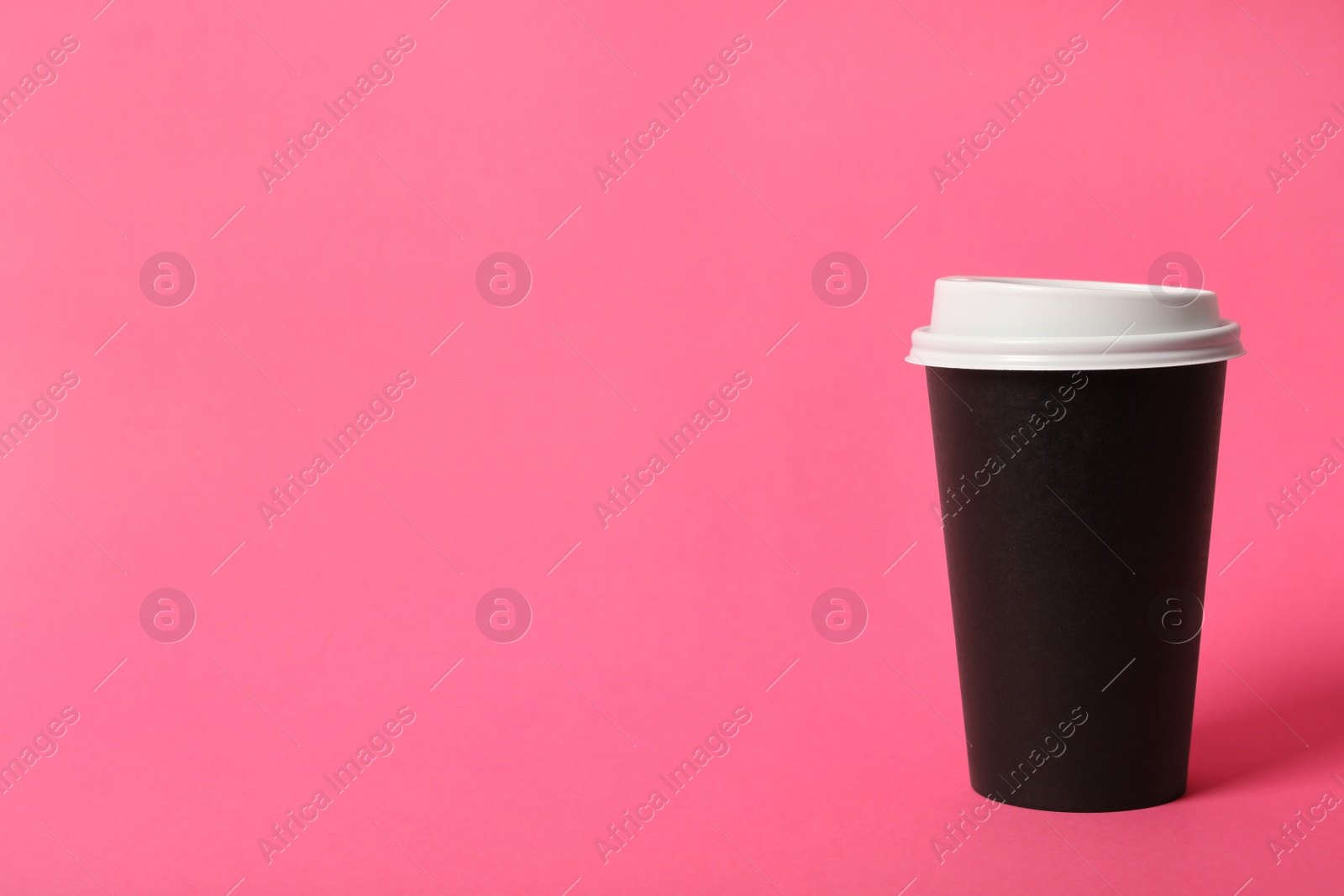 Photo of Takeaway paper coffee cup on pink background. Space for text