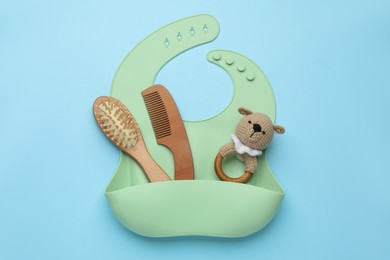 Photo of Baby accessories and bib on light blue background, top view