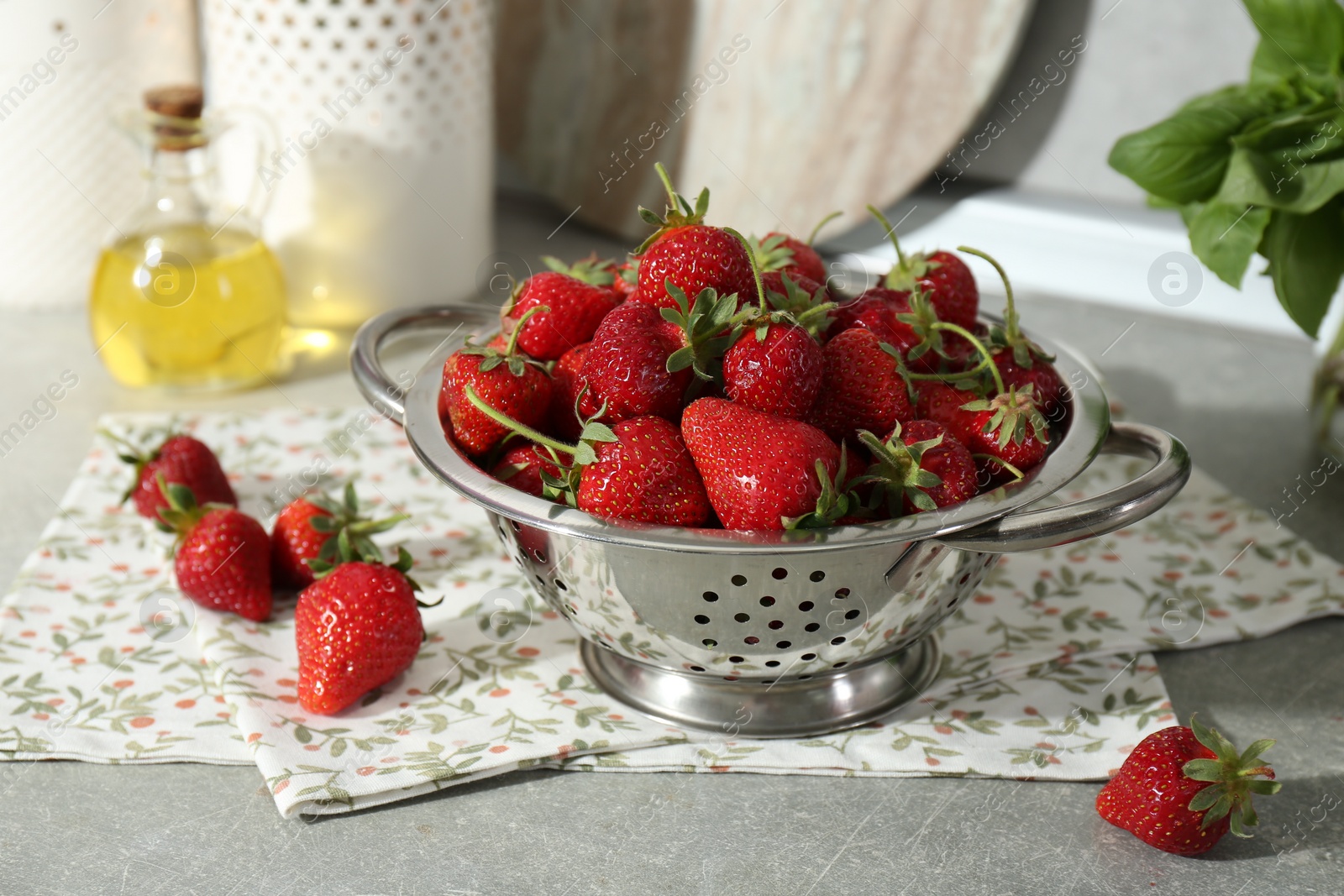 Photo of Metal colander with fresh strawberries on grey countertop in kitchen