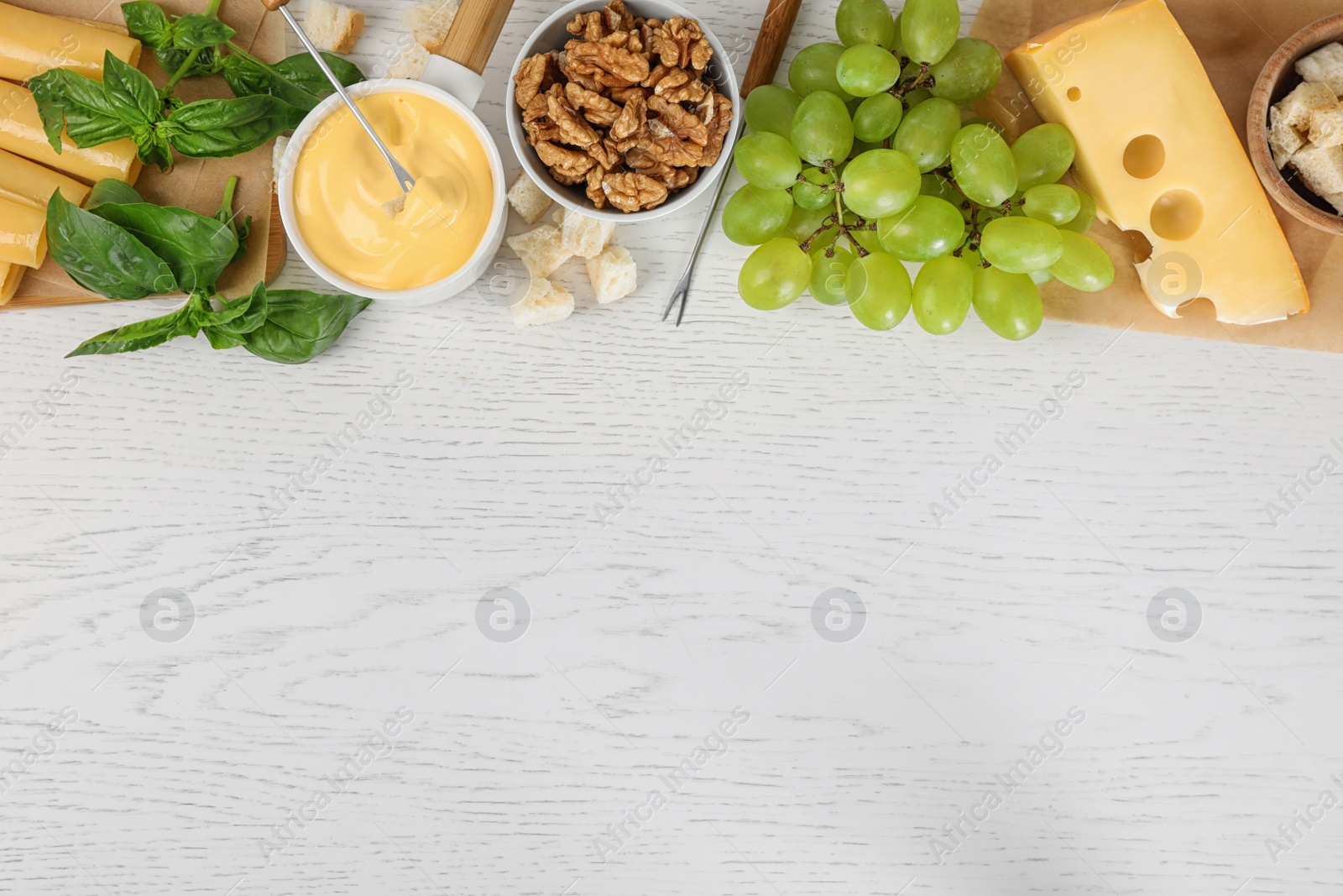 Photo of Flat lay composition with pot of tasty cheese fondue and products on white wooden table, space for text