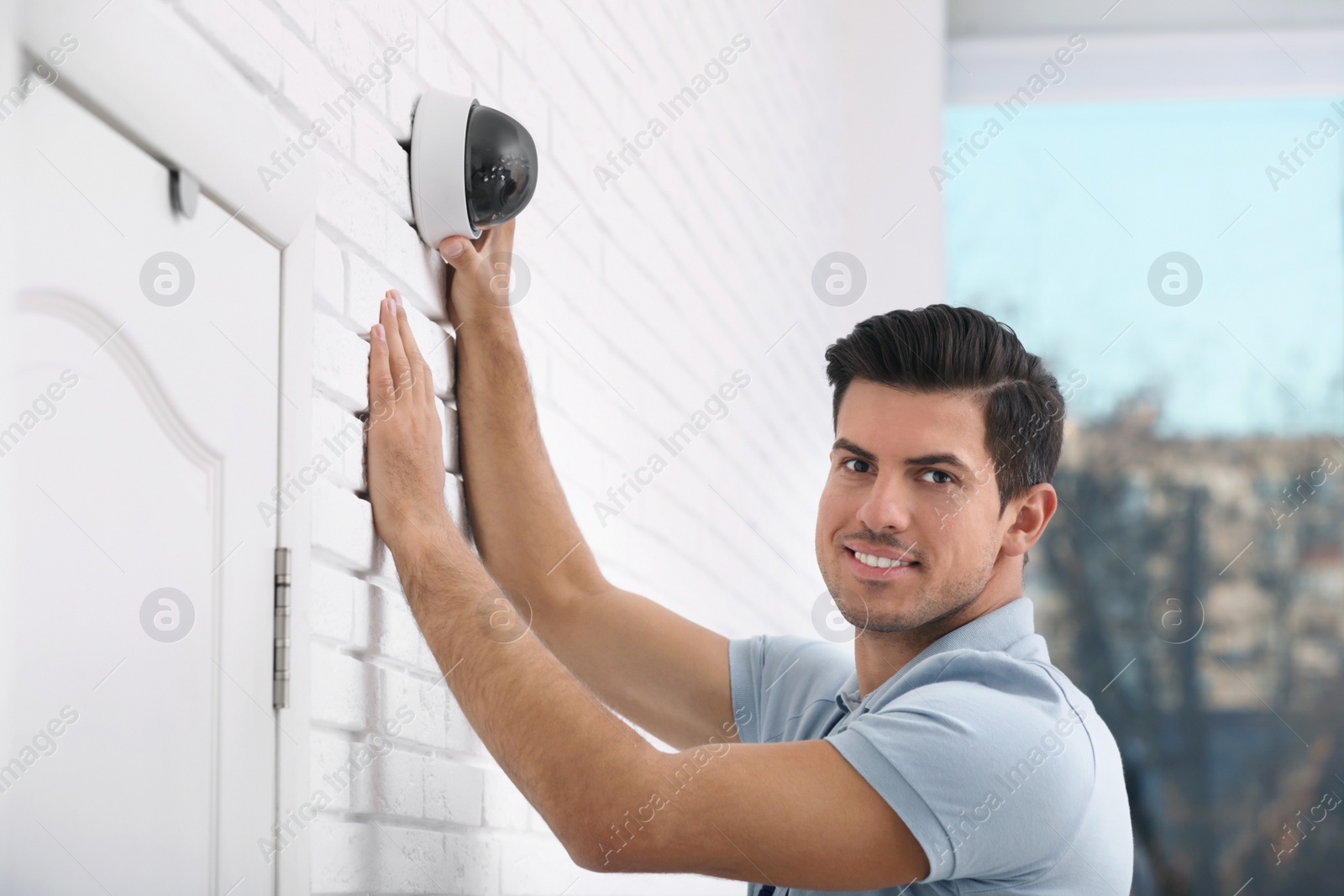 Photo of Technician installing CCTV camera on wall indoors