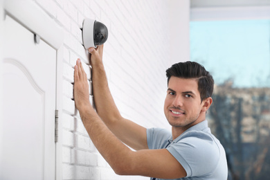 Technician installing CCTV camera on wall indoors