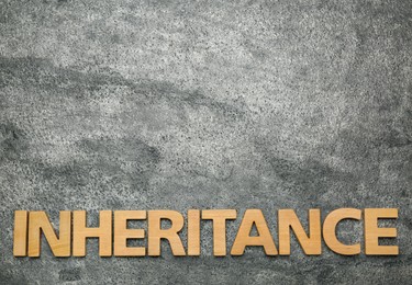 Photo of Word Inheritance made with wooden letters on grey background, flat lay. Space for text