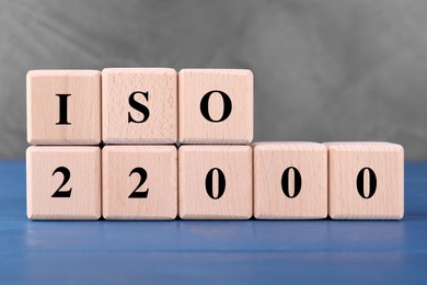Photo of International Organization for Standardization. Cubes with abbreviation ISO and number 22000 on blue wooden table