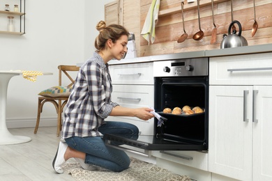 Young woman baking cookies in oven at home