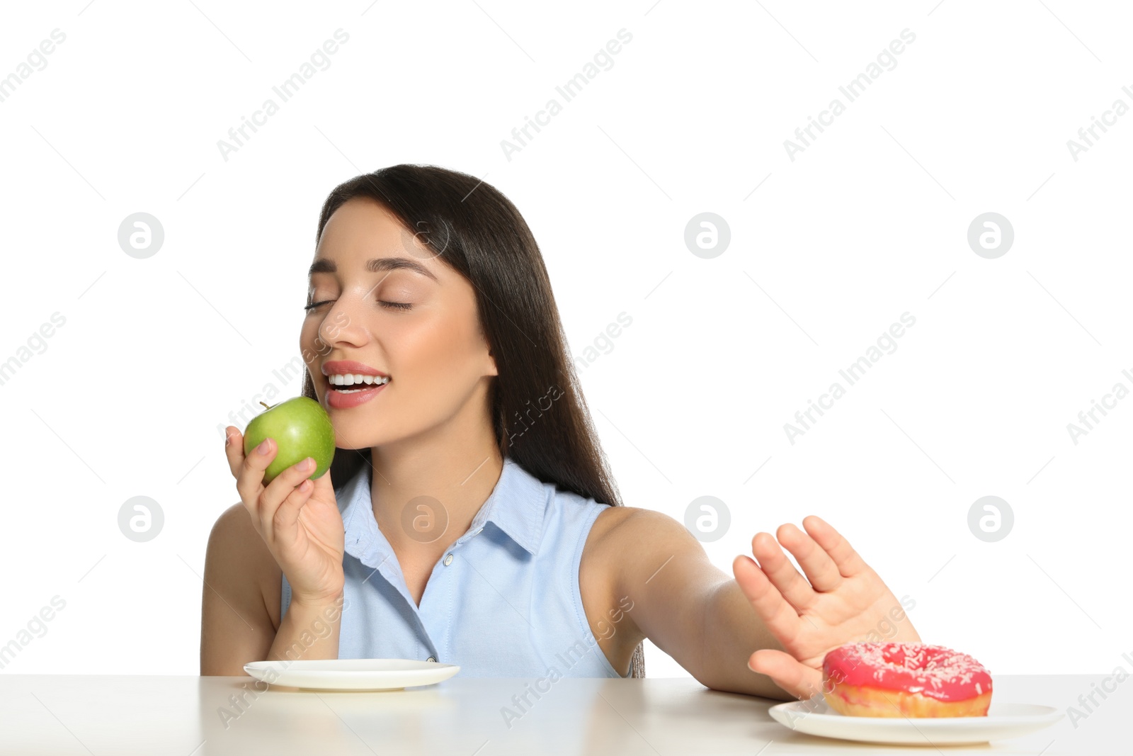 Photo of Woman choosing between apple and doughnut at table on white background