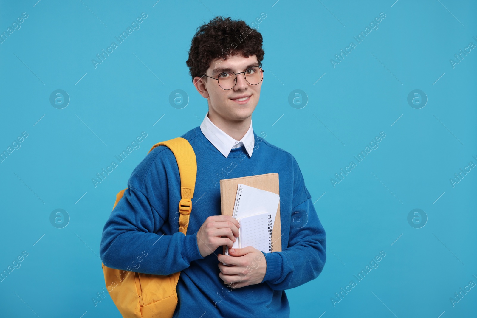 Photo of Portrait of student with backpack and notebooks on light blue background