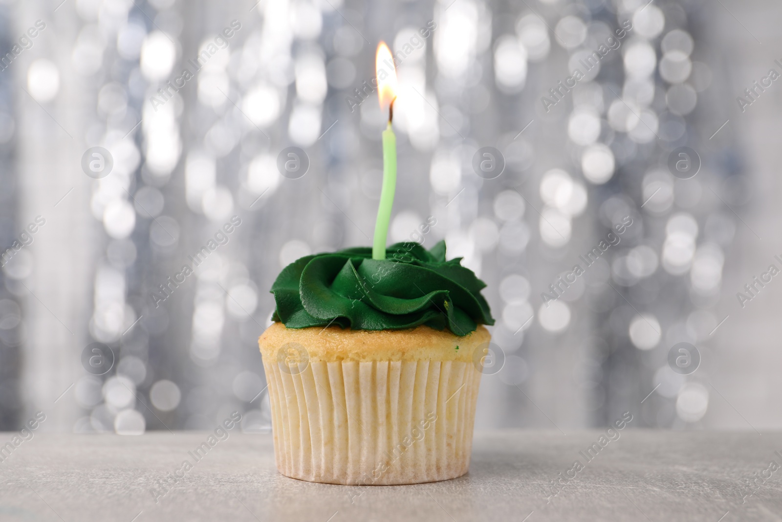 Photo of Delicious cupcake with bright cream and burning candle on grey table, closeup