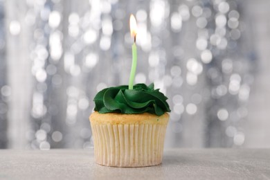 Photo of Delicious cupcake with bright cream and burning candle on grey table, closeup