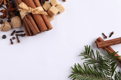 Different spices, nuts and fir branches on white table, flat lay. Space for text