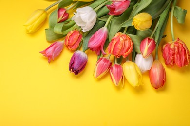 Photo of Beautiful colorful tulip flowers on yellow background, flat lay. Space for text