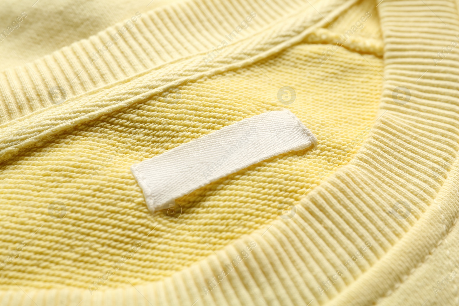 Photo of Blank clothing label on yellow sweater, closeup