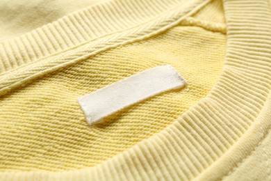 Photo of Blank clothing label on yellow sweater, closeup