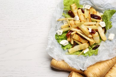 Delicious parsnip with lettuce, feta cheese and dates on white wooden table, flat lay. Space for text