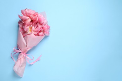 Photo of Beautiful bouquet of pink peonies on light turquoise background, top view. Space for text
