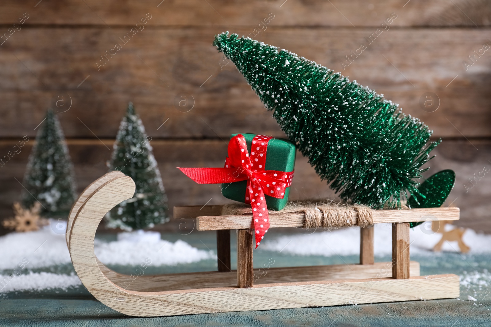 Photo of Sleigh with decorative Christmas tree and gift box on blue wooden table