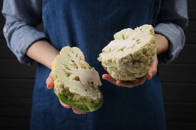 Photo of Woman holding fresh cauliflower against dark background, closeup