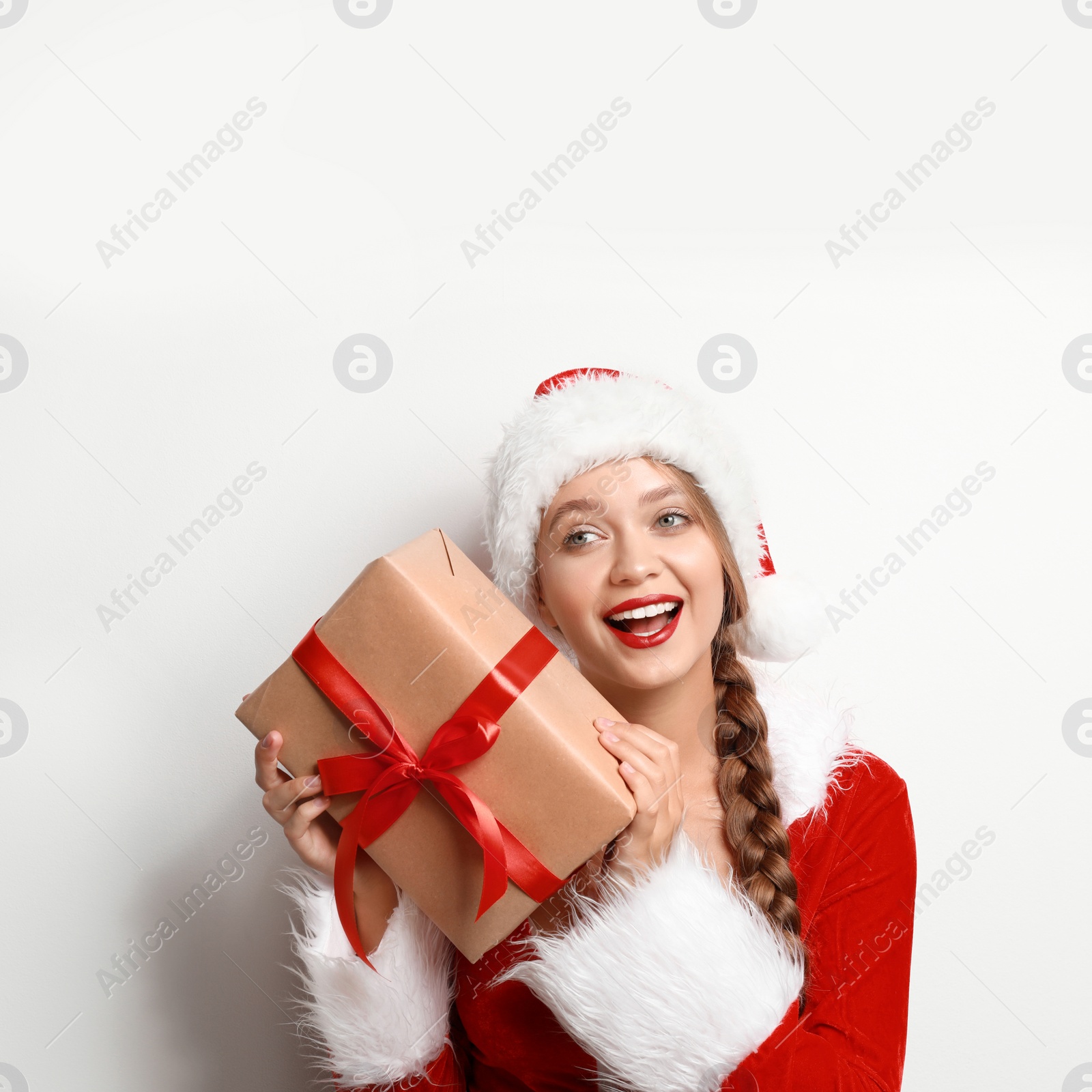 Photo of Beautiful Santa girl with Christmas gift on light background