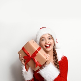 Beautiful Santa girl with Christmas gift on light background