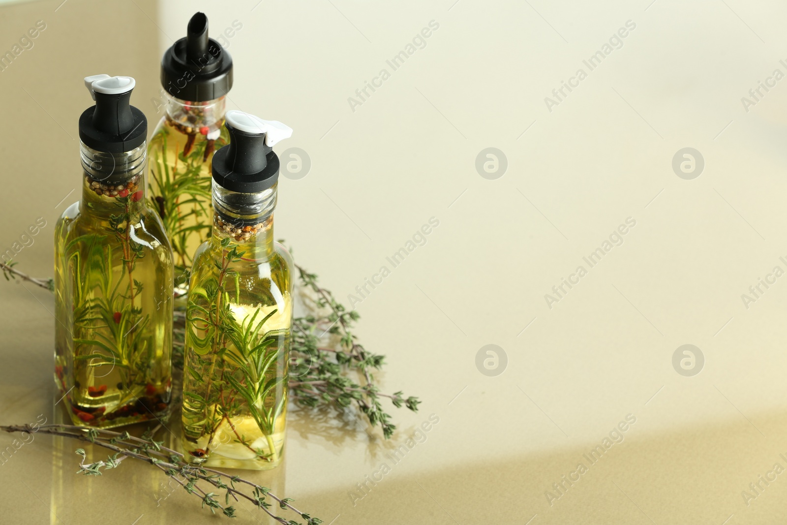 Photo of Cooking oil with different spices and herbs in bottles on colorful table. Space for text