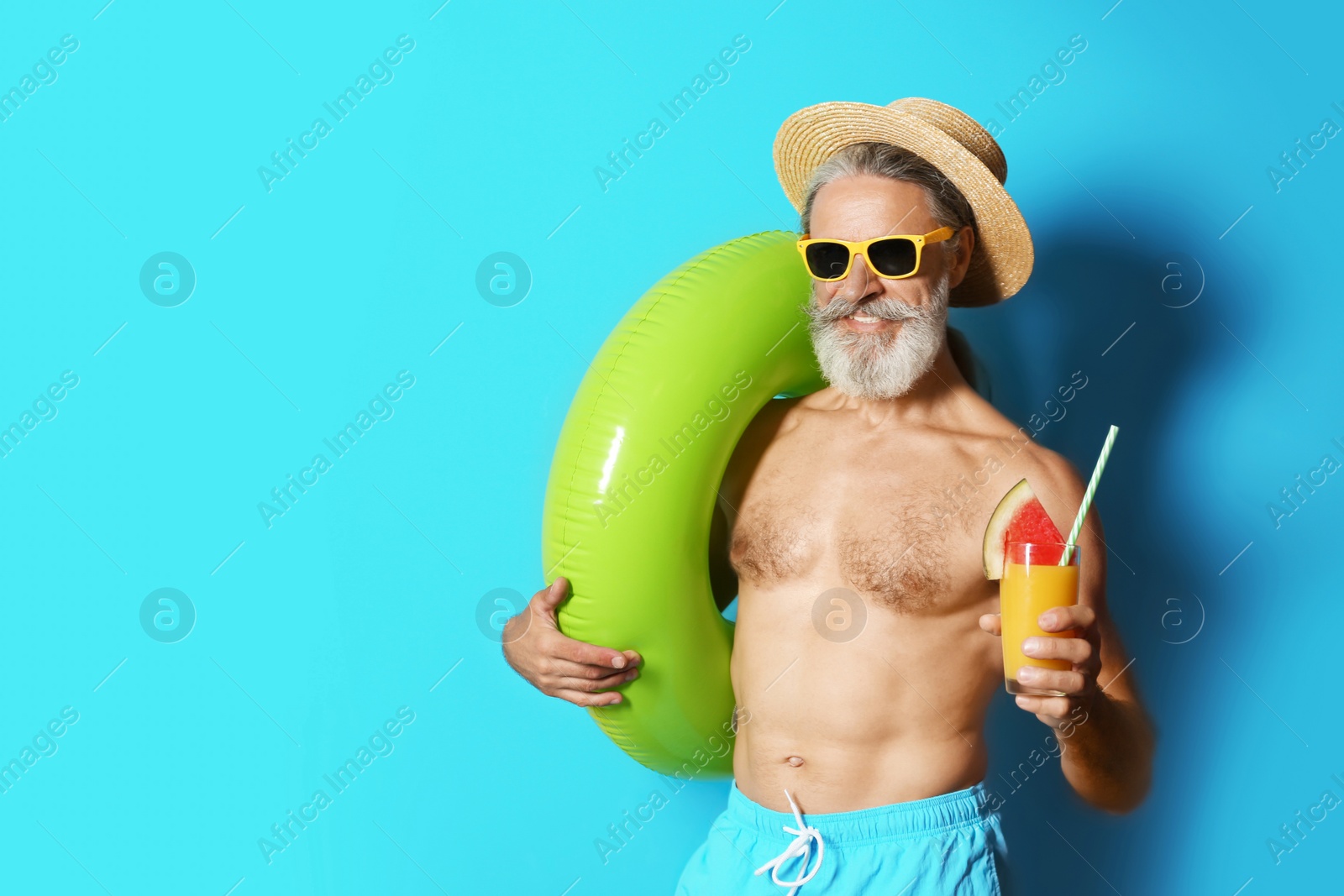 Photo of Shirtless man with inflatable ring and glass of cocktail on color background