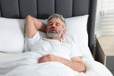 Photo of Man snoring while sleeping in bed at home