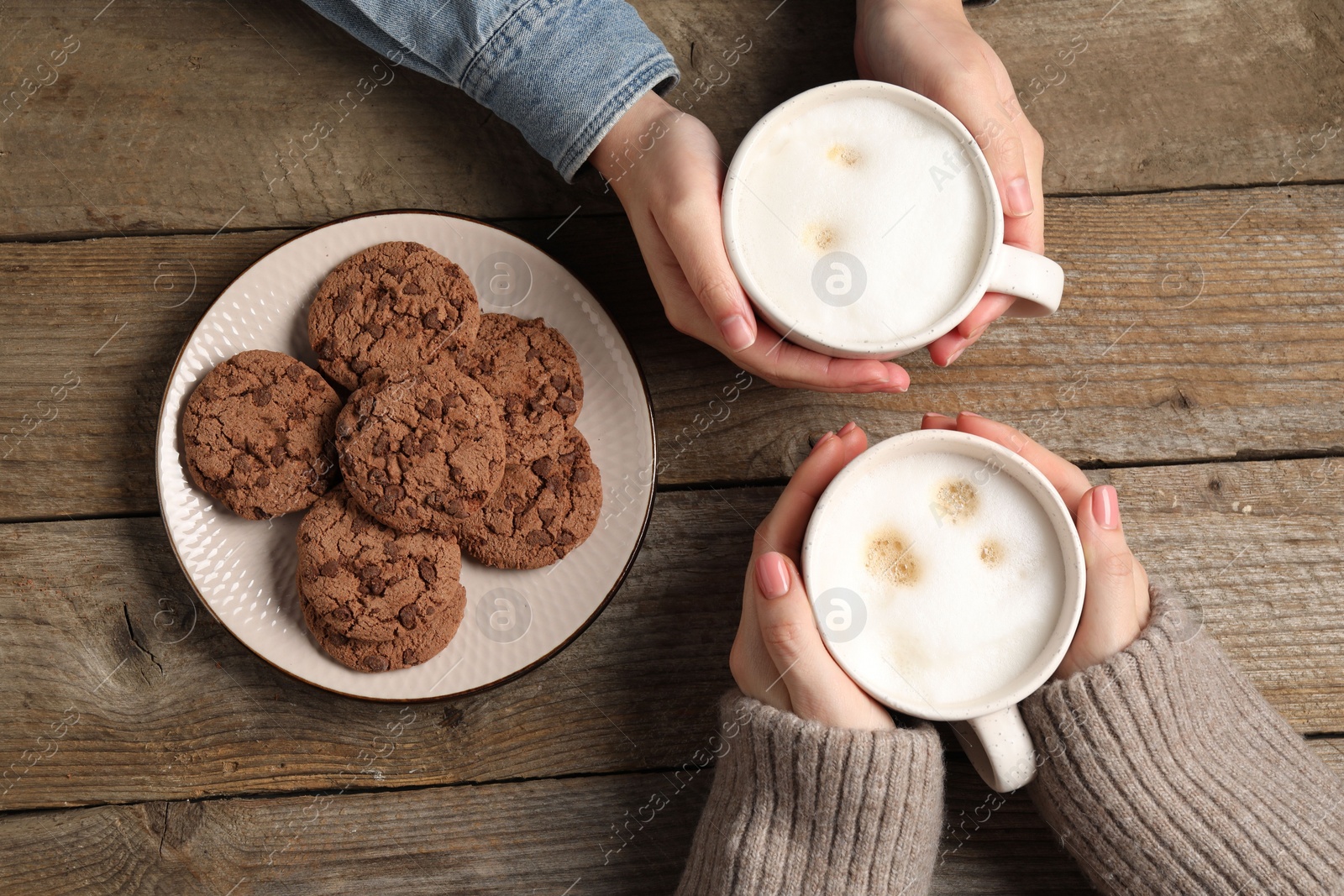 Photo of Women having coffee break at wooden table, top view