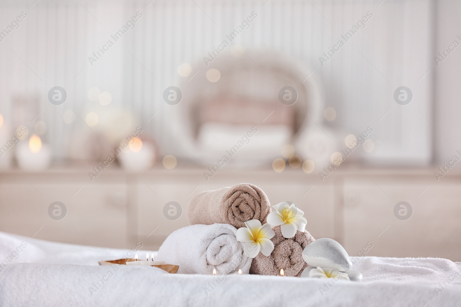 Photo of Towels and candles on massage table in modern spa salon. Place for relaxation