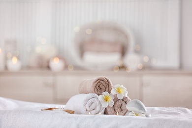 Photo of Towels and candles on massage table in modern spa salon. Place for relaxation