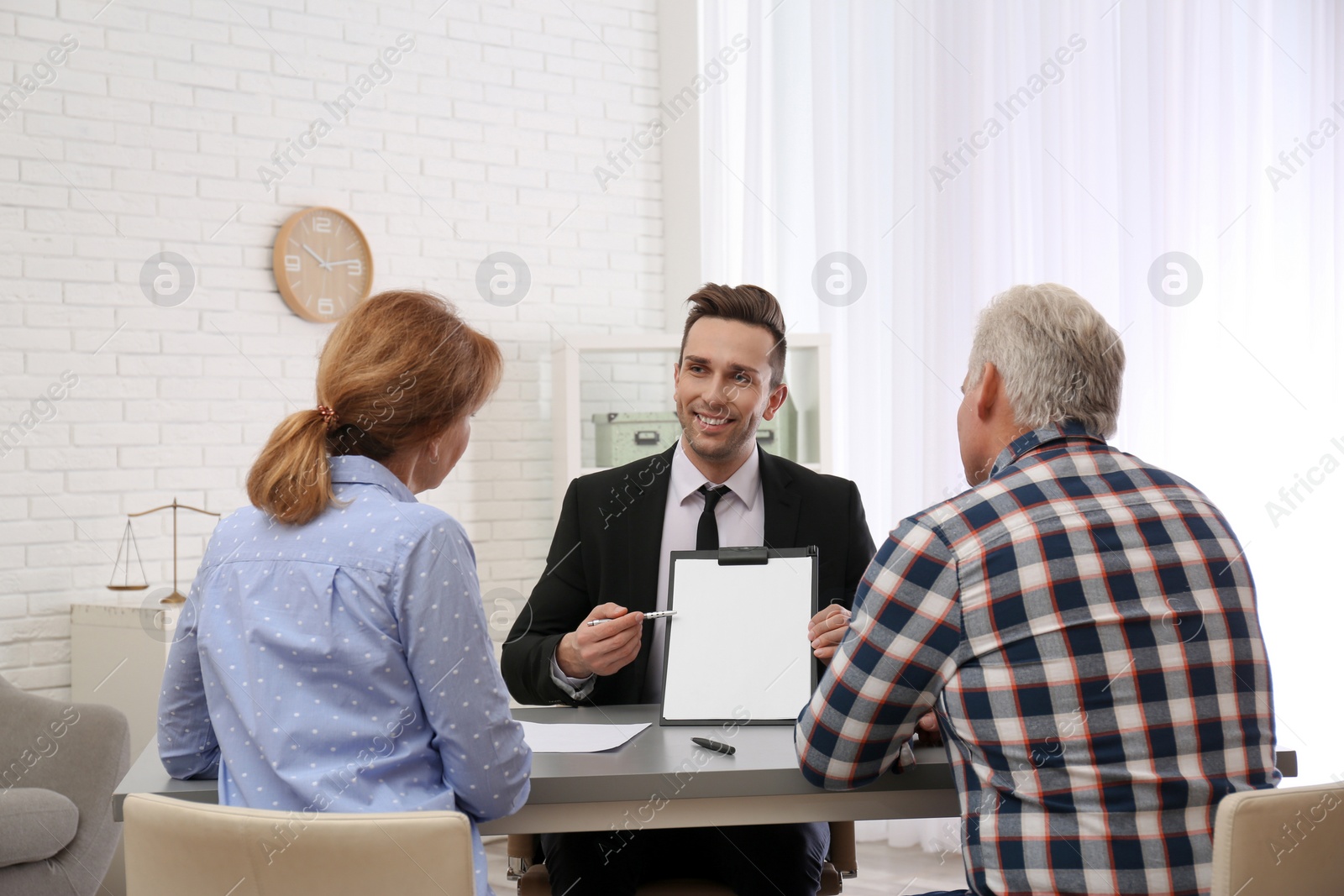 Photo of Young lawyer consulting senior couple in office